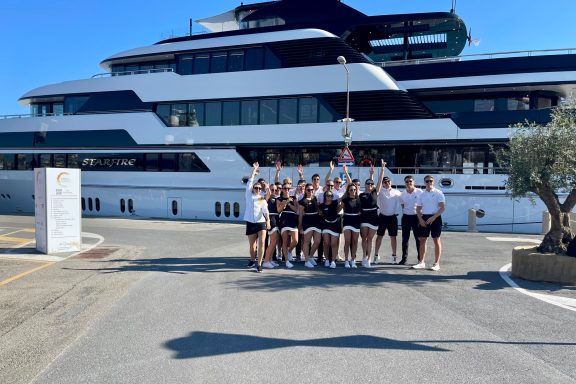 Crew of Superyacht STARFIRE pose in front of yacht