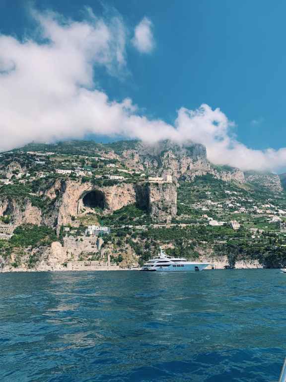 Breathtaking view of the Amalfi Coast featuring rugged cliffs and a yacht on the Mediterranean Sea.
