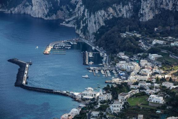 Scenic aerial view of the marina and coastline in Capri, Italy, showcasing Mediterranean beauty.